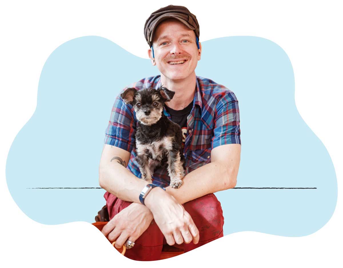 A man sitting with his small dog on his lap smiling