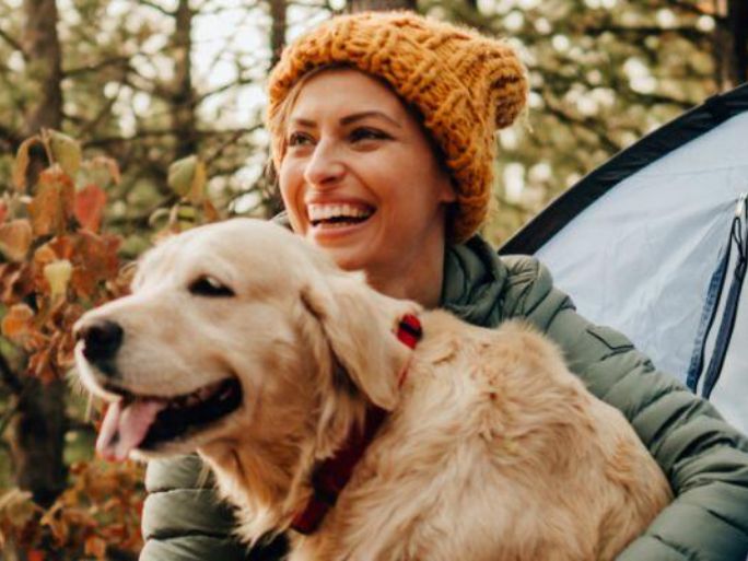 A woman sitting outside with a golden retriever