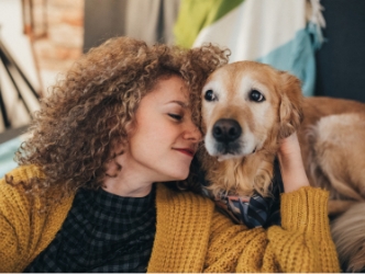 A woman nuzzling her senior golden retriever.